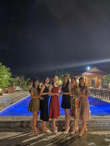 een groep vrouwen die 's nachts bij een zwembad staan bij An Ngoc Tam Coc Bungalow in Ninh Binh