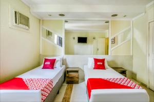 two beds in a room with red pillows at OYO Nobs Hotel, São João de Meriti in São João de Meriti
