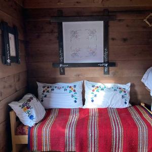 um quarto com uma cama com um cobertor vermelho e almofadas em Household Babovic - Old house Miljan's valley em Andrijevica