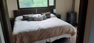 Un dormitorio con una cama blanca con almohadas y una ventana en Le Fario Lodge in Patagonia en Lago Futalaufquen