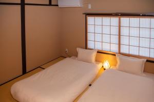 2 camas en una habitación pequeña con ventana en 京町屋の宿 天神庵, en Kioto