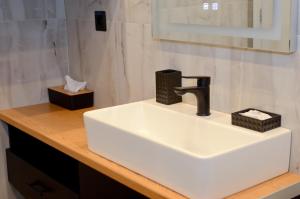 un bancone del bagno con lavandino bianco e specchio di Roloi suites a Nafpaktos Altre 37 foto