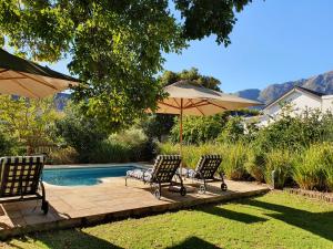 two chairs and an umbrella next to a pool at Petit Ermitage in Franschhoek