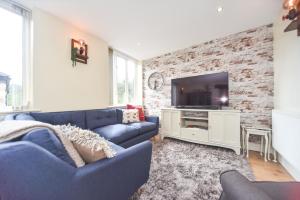 a living room with a blue couch and a tv at Coach House Mews in Matlock Bank