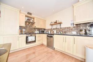 a large kitchen with wooden floors and white cabinets at Coach House Mews in Matlock Bank