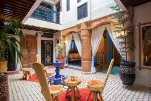 una sala de estar con mesas y sillas y una habitación con en Riad Christina, en Marrakech