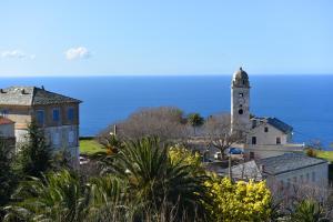 a small town with a clock tower on a hill at GITE DES MOINES-Canelle in Canari