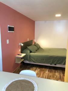 1 dormitorio con cama verde y pared roja en Los Naranjos Apart Hotel en Villa Carlos Paz