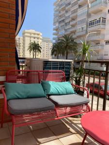 un banco rojo con almohadas azules en el balcón en Apartament Roma V, Playa Gandia, en Gandía