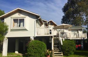 Cette maison blanche dispose d'un balcon et d'un parasol. dans l'établissement Gran casa en Isla Negra, à Isla Negra