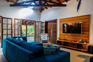 a living room with blue furniture and a flat screen tv at Casa Tubarão - A Melhor in Camburi