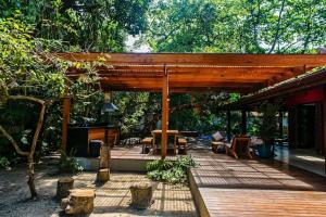a wooden pergola with tables and chairs on a deck at Casa Tubarão - A Melhor in Camburi