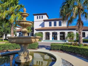 une fontaine en face d'une maison avec des palmiers dans l'établissement Luxury 7BR 6BA Home Private Pool and BBQ only13min to Disney 4788 sqft, à Kissimmee