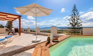 - Piscina con sombrilla y mesa con botella de vino en Villa di Creta Heated Pool, en Kalyves