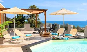 una piscina con sillas y sombrillas junto al océano en Villa di Creta Heated Pool, en Kalyves