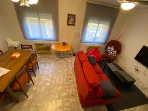 Una sala de estar con un sofá rojo y una mesa. en CASA LOS PILARES, en San Bartolomé de Pinares