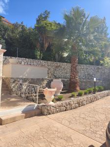a stone wall with a bench and a palm tree at Villa angiole in Castellonorato