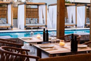 uma mesa com garrafas de vinho ao lado de uma piscina em Skiathos Theros, Philian Hotels and Resorts em Skiathos