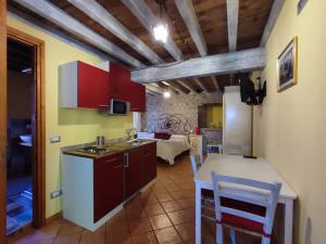 モンツァンバーノにあるCorte Davini Agriturismoのキッチン(赤いキャビネット、テーブル、椅子付)