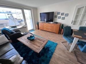 ein Wohnzimmer mit einem Sofa, einem Tisch und einem TV in der Unterkunft Luxus-Loft-Sylt Haus Dünenburg in Westerland