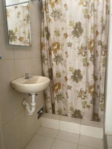 a bathroom with a sink and a shower curtain at Hotel Calmelia in Piura