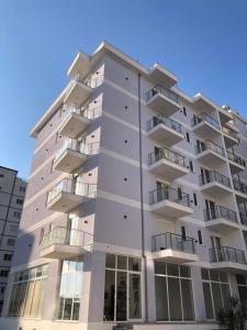 un edificio de apartamentos alto y blanco con balcones en Hotel MARIO, Shengjin, en Lezhë