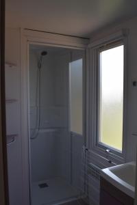 a bathroom with a shower and a sink and a window at Camping La Croix Badeau in Soulaines-Dhuys