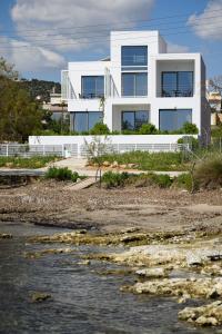 a white house with a river in front of it at CUBES ON THE BEACH Athens Airport in Artemida