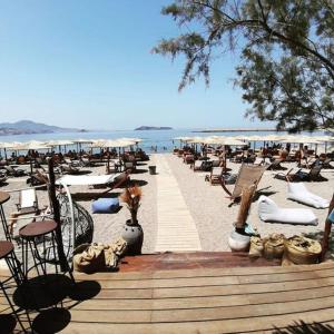 una spiaggia con sedie e ombrelloni e l'oceano di Gaea Gardens Studios & Villas a Pétra