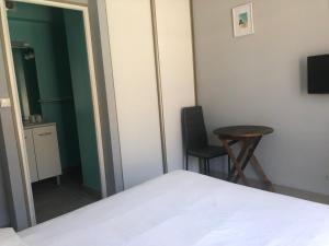 a bedroom with a bed and a table and a chair at Les Chambres des Gites des Isles in Barneville-Carteret
