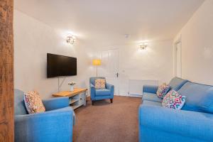 un salon avec deux canapés bleus et une télévision dans l'établissement Cottage 2, Old Farmhouse Mews, à Braithwaite