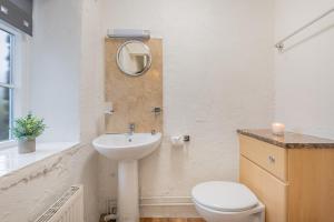 une salle de bain avec un lavabo, des toilettes et un miroir dans l'établissement Cottage 2, Old Farmhouse Mews, à Braithwaite 3 autres photos