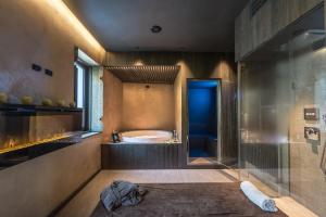 La salle de bains est pourvue d'une baignoire et d'une douche en verre. dans l'établissement Good Life Hotel Garden, à Ledro