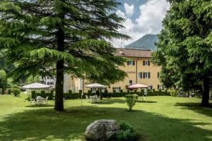 un edificio con mesas y sombrillas en un parque en Good Life Hotel Garden, en Ledro