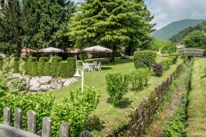 un jardín con mesas, sombrillas y una valla en Good Life Hotel Garden, en Ledro