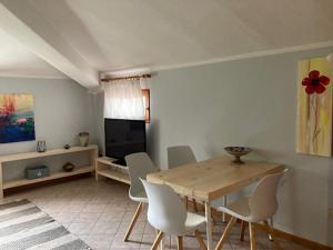 a dining room with a wooden table and white chairs at AL CLISI graziosa mansarda in Villanuova sul clisi