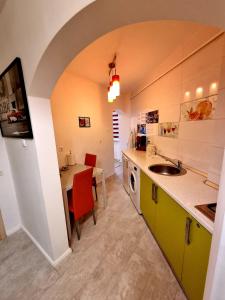 cocina con fregadero y mesa con sillas rojas en Apartament Faleza, en Galaţi