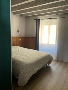 a bedroom with a bed and a window at Duplex avec poêle à granulés et garage à motos in Montaigut-le-Blanc