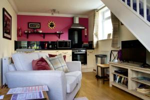 a living room with a white chair and a kitchen at Rowan House B&B Rooms & A Self Catering Apartment in Lochgoilhead