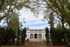 une grande maison blanche avec des arbres devant dans l'établissement La Casa del Valle . Descansar junto a Doñana en plena naturaleza., à Manzanilla