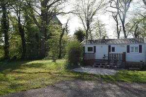une cabine blanche avec un banc dans l'herbe dans l'établissement Camping La Croix Badeau, à Soulaines-Dhuys
