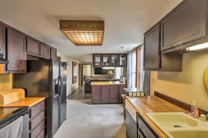 a kitchen with wooden cabinets and a kitchen with a sink at Downtown Sheboygan Apartment with Private Deck! in Sheboygan