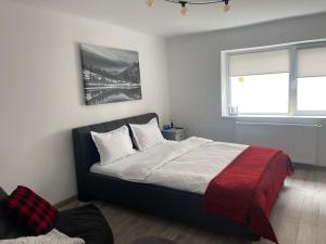 sypialnia z łóżkiem z czerwonym kocem i oknem w obiekcie Maple Lodge Apartments w Braszowie