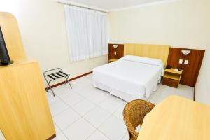 Habitación de hotel con cama y TV en Hotel Plaza Mar, en Vila Velha