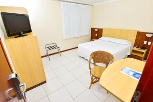 a hotel room with two beds and a television at Hotel Plaza Mar in Vila Velha