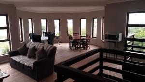 a living room with a couch and a table and chairs at Stonehouse on Main in Struisbaai