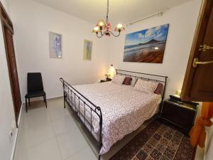 1 dormitorio con cama y lámpara de araña en Almendro, en Arico Viejo