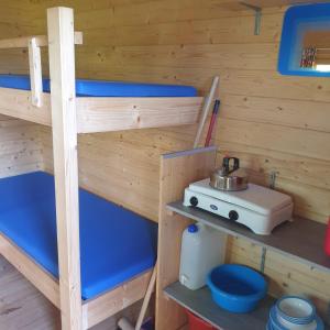 a bunk bed in a wooden room with a stove at Blokhut Camping Alkenhaer in Appelscha