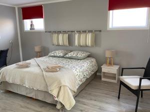 a bedroom with a bed and a chair and two windows at LE DOMAINE DES SAULES in Richebourg