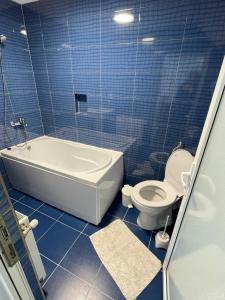 W wyłożonej niebieskimi kafelkami łazience znajduje się wanna i toaleta. w obiekcie Casa Luca Ama Bran w mieście Bran